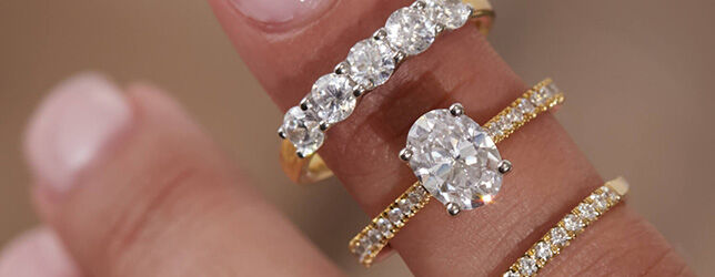 Oval solitaire engagement ring and five-stone diamond band styled with yellow gold pav&eacute; rings